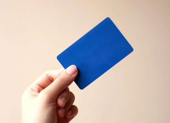 "A hand holding a blank blue card